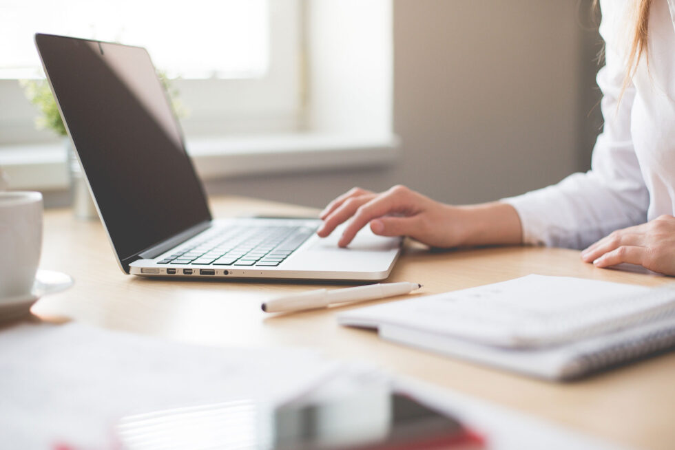 close up of desk and woman working at laptop