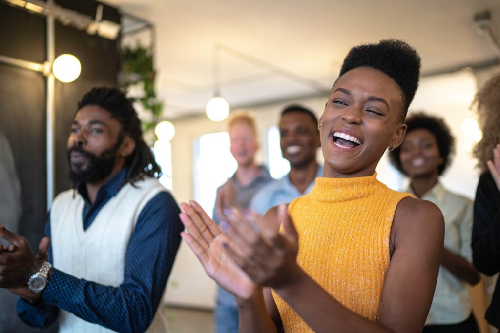 employees celebrating and clapping and smiling in meeting