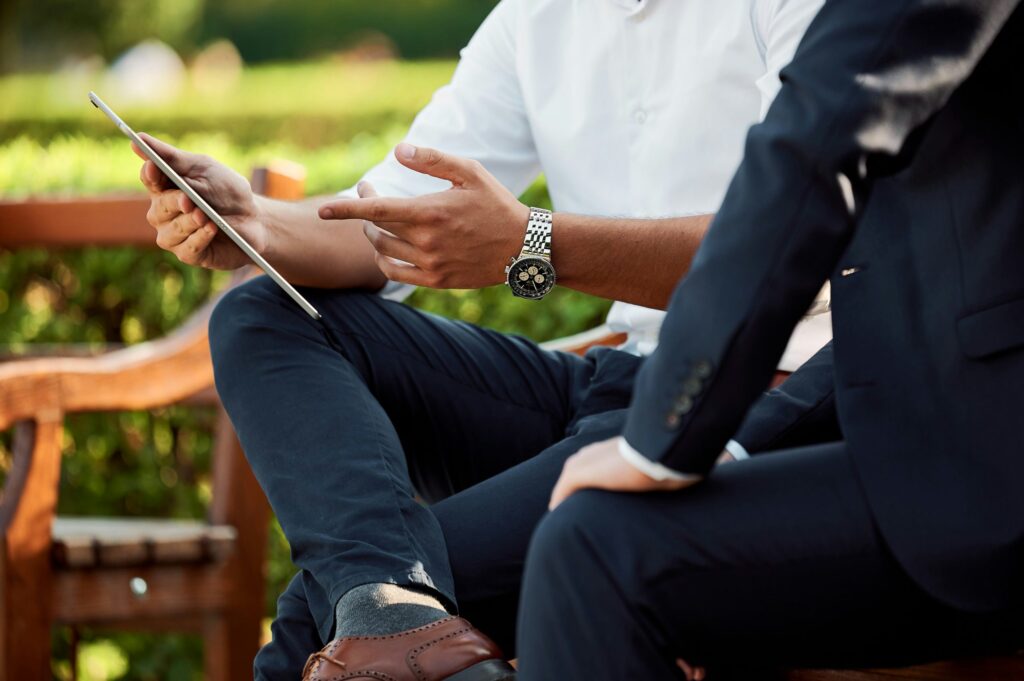 men outside sat discussing business with ipad