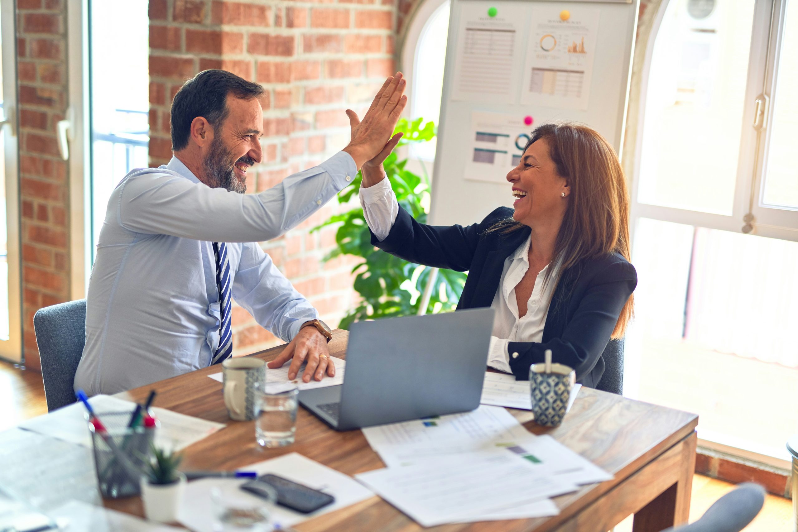employees high fiving over a laptop