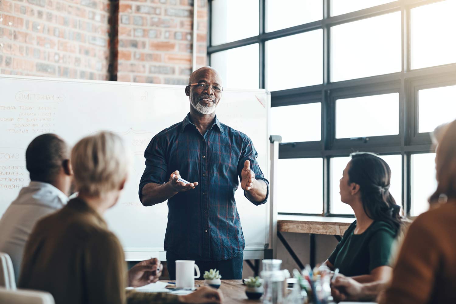 man stood in front of whiteboard presenting to room