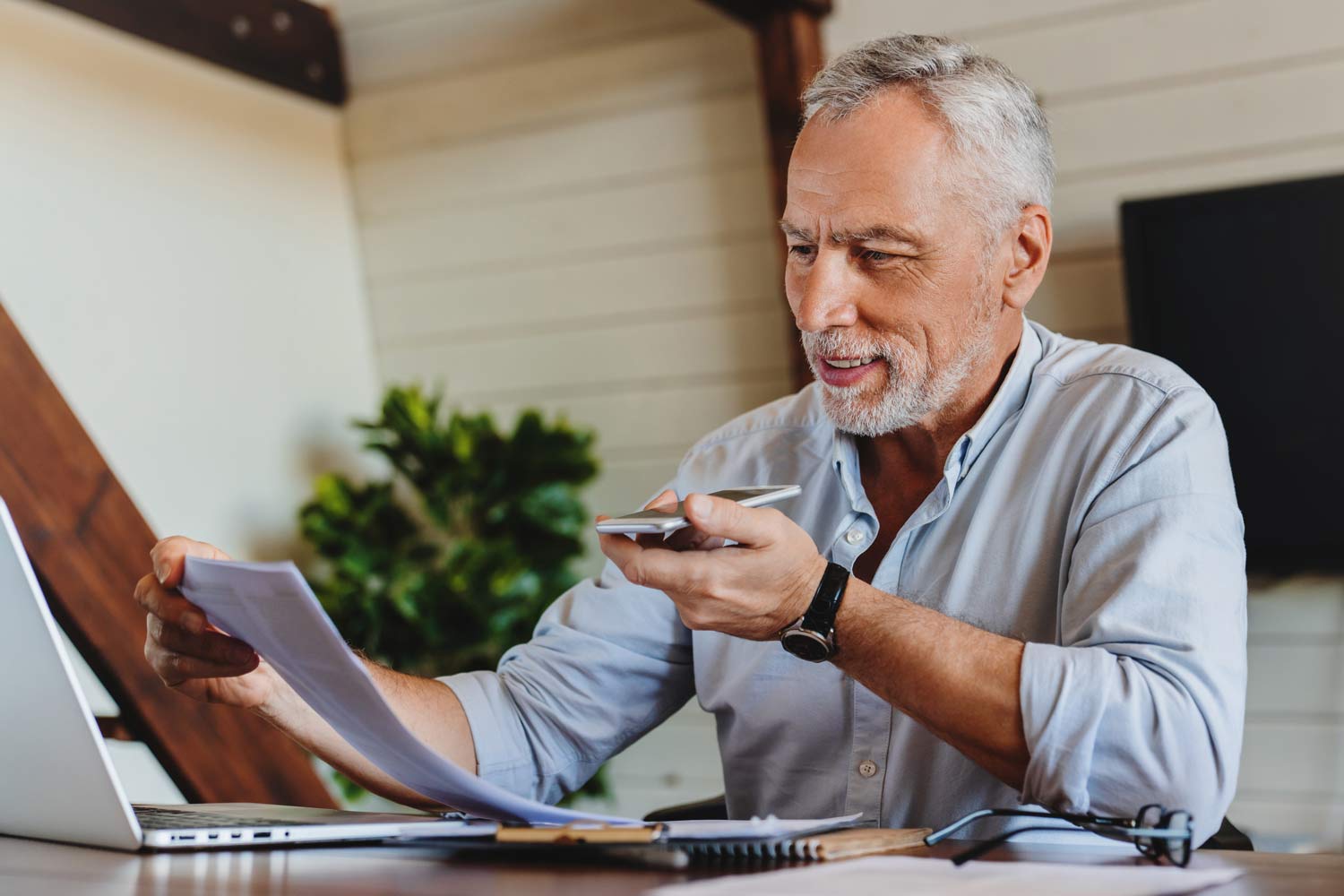 man at laptop looking at document and on speaker phone